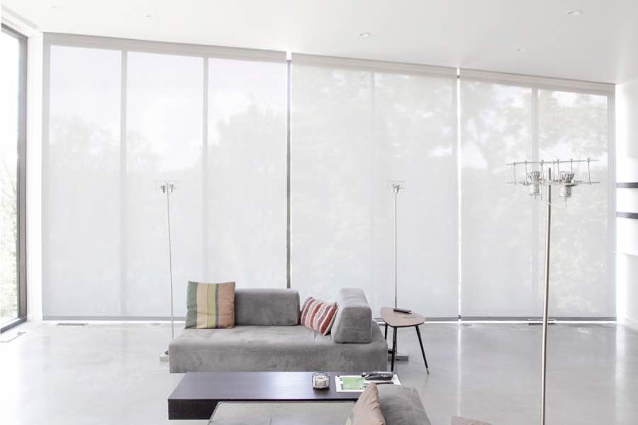 Motorized window shades make controlling natural light effortless in your Atlanta great room. White motorized shades on a wall of tall great room windows