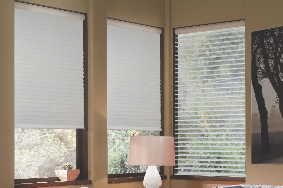 Opaque motorized window shades in Atlanta keep hot UV rays out of your home. Gray motorized sheer shades on corner windows next to gray furniture