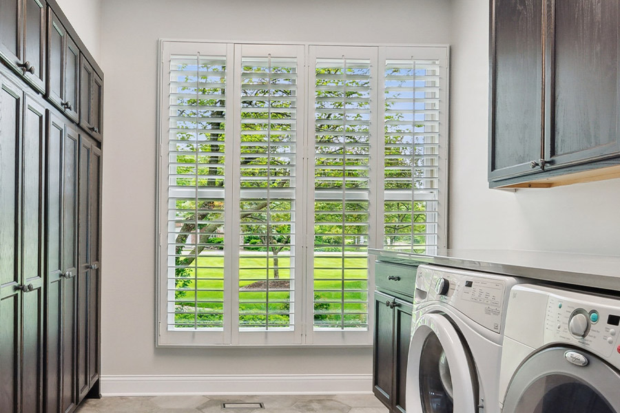 Find the perfect level of natural light for your Atlanta laundry room with interior shutters. White Polywood shutters letting light through a laundry room window