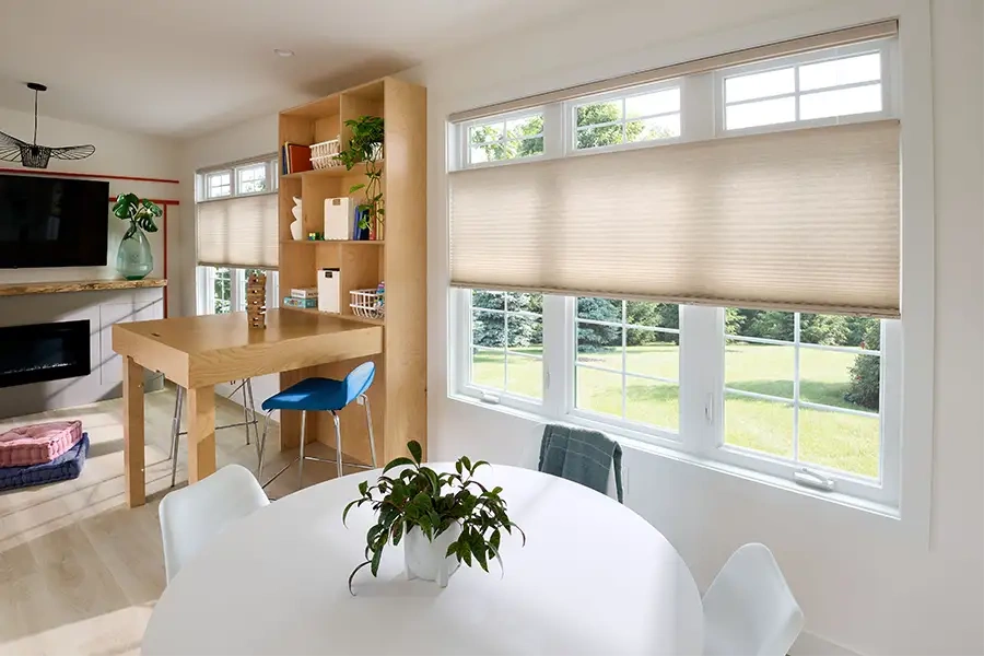 If retrofitting an existing space like this modern dining room, battery-powered motorized shades are a more convenient option. Beige cellular shades in a modern dining area