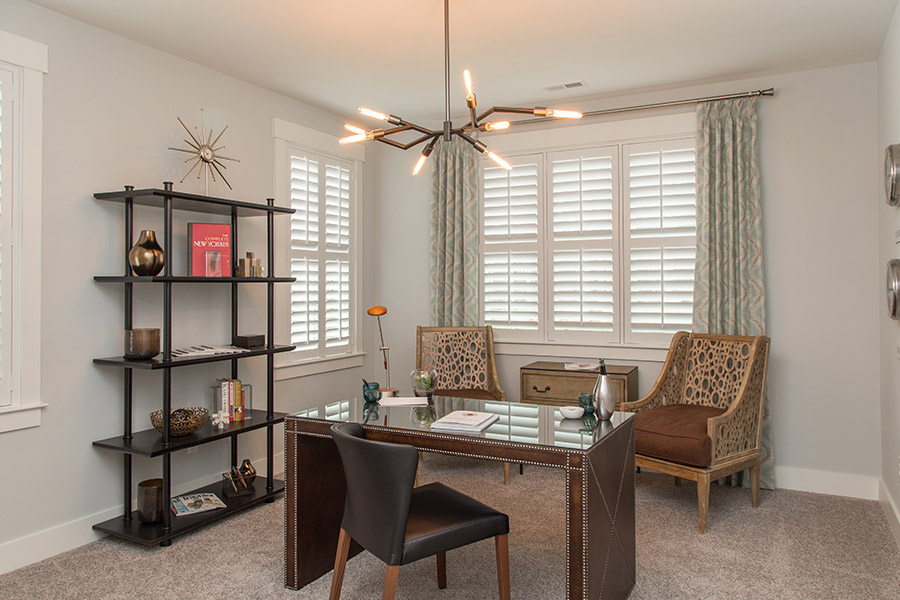 Colorful curtains can add a bit of flair with white Polywood shutters in Atlanta. Sage green patterned curtains on white polywood shutters in an office.