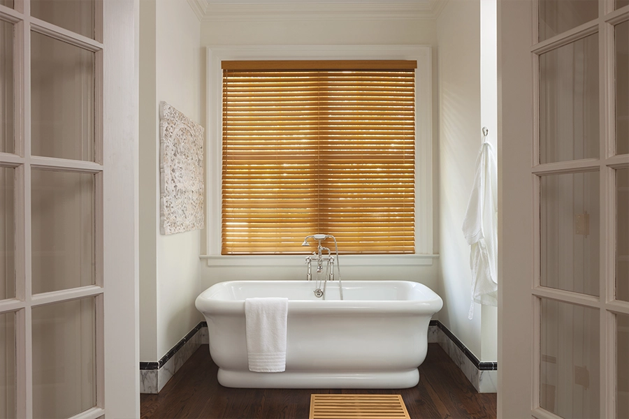 Brown faux wood blinds on a window over a bathtub