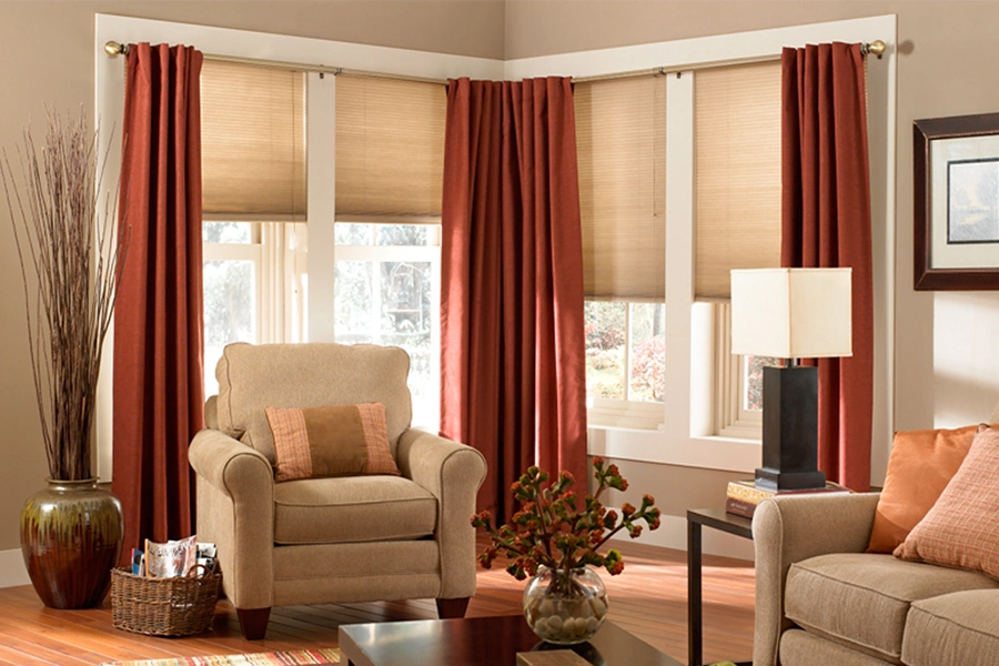 Beige cellular shades layered with drapes in a stylish living space